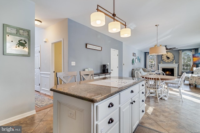 kitchen featuring a center island, light tile patterned floors, electric stovetop, pendant lighting, and white cabinets