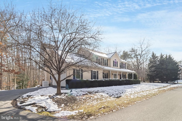 snow covered property featuring a porch and central air condition unit