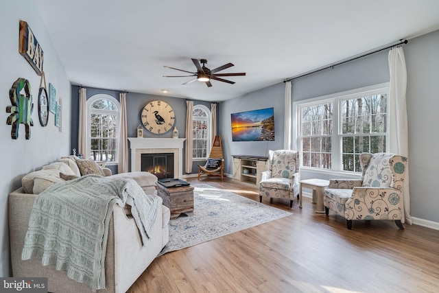 living room featuring a tile fireplace, wood-type flooring, and ceiling fan