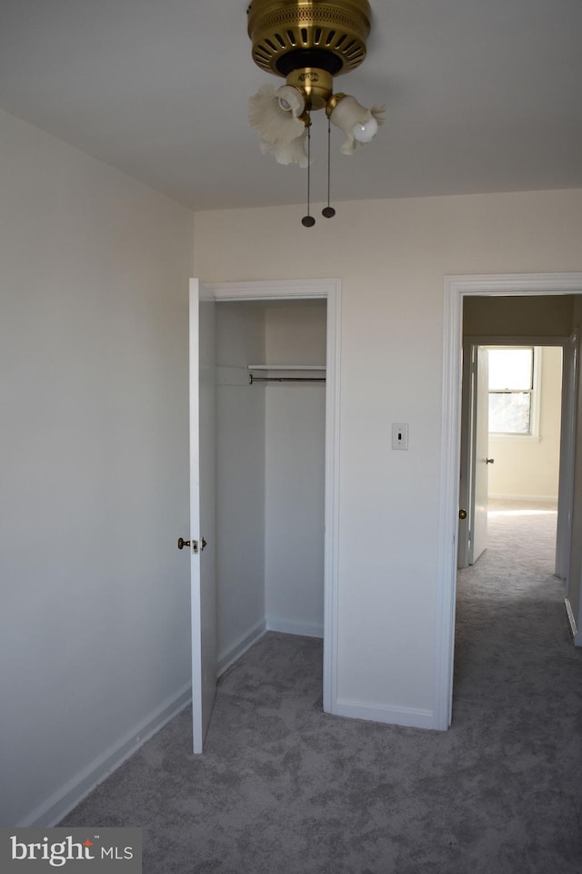 unfurnished bedroom with ceiling fan, dark carpet, and a closet