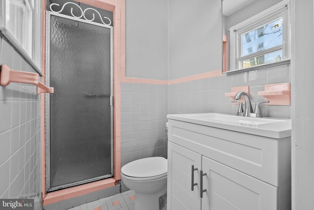 bathroom with tile patterned flooring, an enclosed shower, tile walls, toilet, and vanity