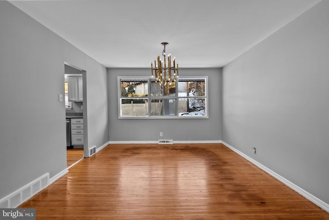 unfurnished dining area with hardwood / wood-style floors and a chandelier