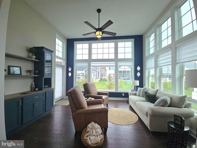 living room with ceiling fan, a high ceiling, and dark hardwood / wood-style floors