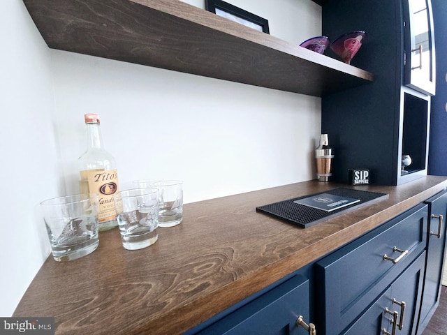 bar with blue cabinetry and butcher block counters