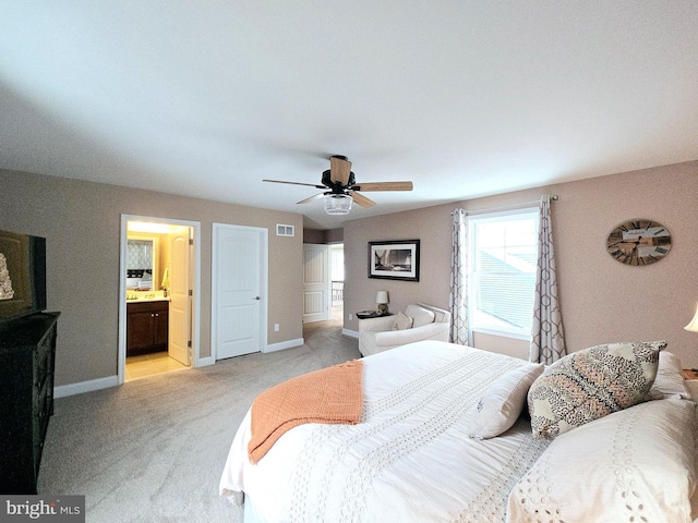 bedroom featuring ceiling fan, light colored carpet, and connected bathroom