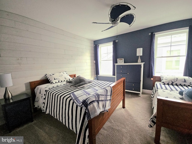 bedroom featuring multiple windows, wooden walls, and ceiling fan