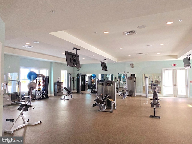 exercise room featuring a tray ceiling and french doors