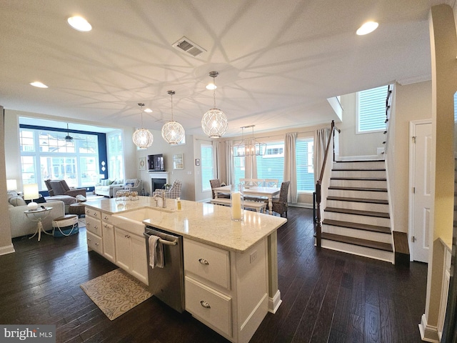 kitchen with pendant lighting, dishwasher, dark wood-type flooring, light stone countertops, and a center island