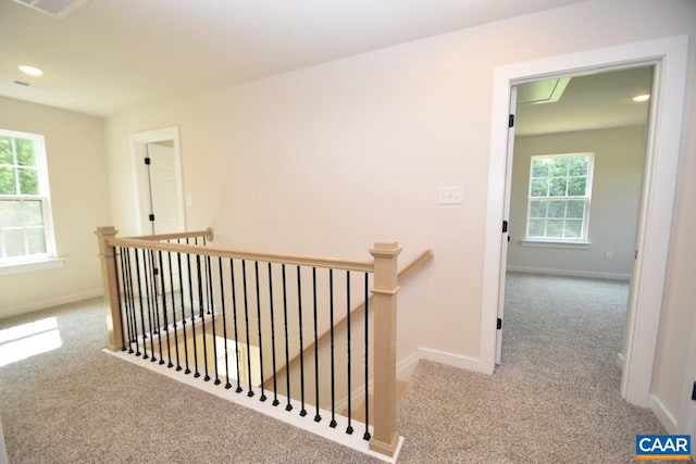 hallway with light colored carpet and a wealth of natural light