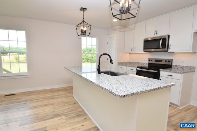 kitchen featuring sink, white cabinets, an island with sink, light stone counters, and electric stove