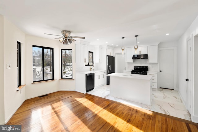 kitchen with a kitchen island, decorative light fixtures, white cabinetry, dishwasher, and range