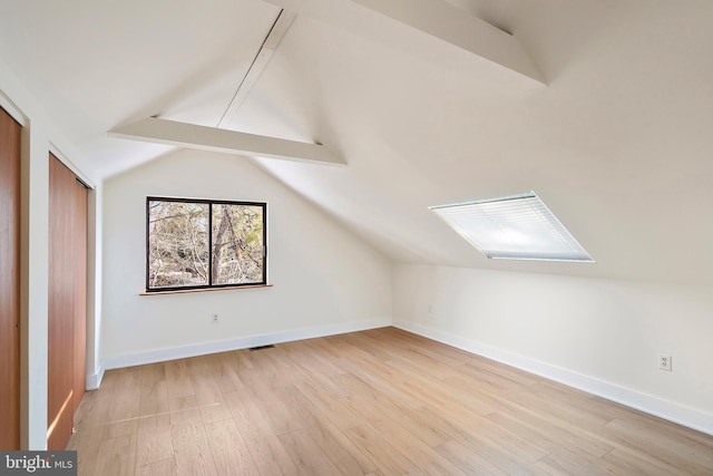 additional living space featuring vaulted ceiling with beams and light wood-type flooring