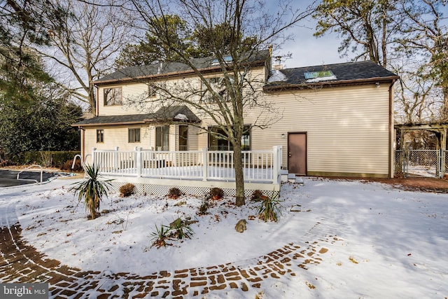 snow covered back of property featuring a deck