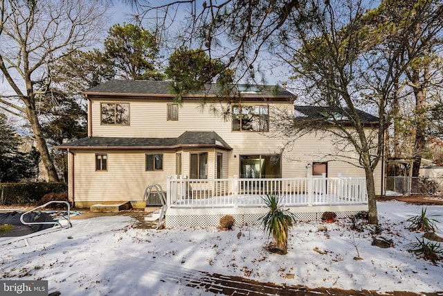 snow covered rear of property featuring a deck