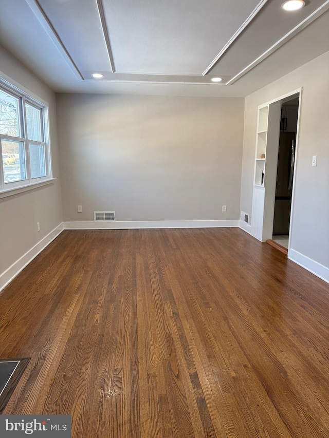 spare room featuring built in shelves and dark wood-type flooring