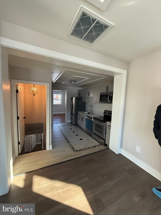 interior space featuring sink, hardwood / wood-style floors, backsplash, and stainless steel appliances