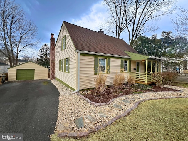 view of front facade with a porch, a chimney, an outdoor structure, and a detached garage