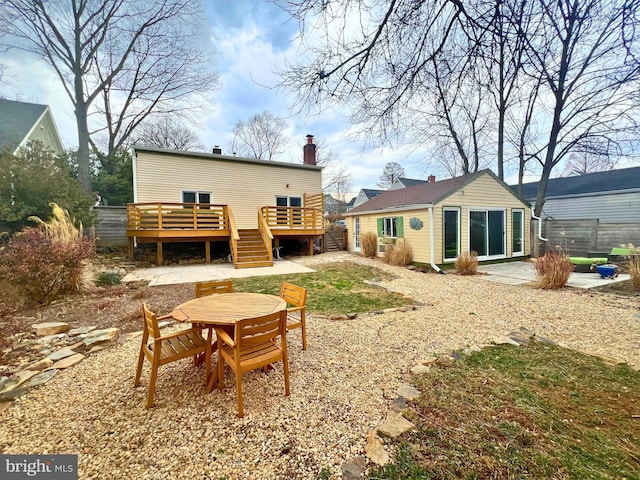 back of house with an outbuilding, a patio, fence, a wooden deck, and a chimney