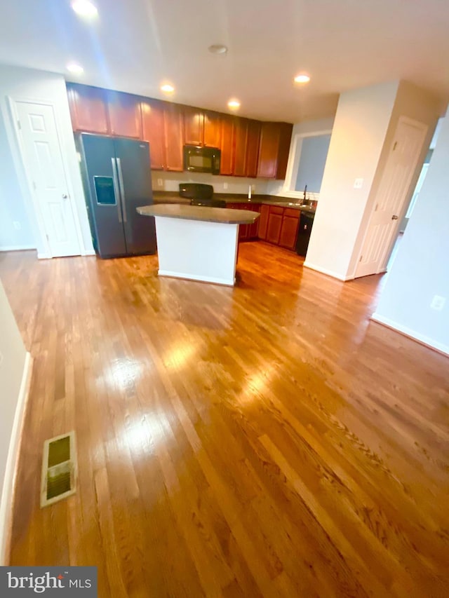 kitchen featuring sink, stove, a center island, stainless steel refrigerator with ice dispenser, and light wood-type flooring