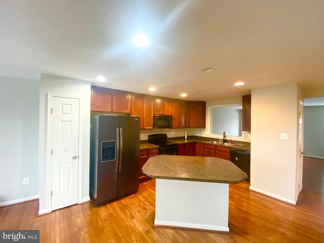 kitchen featuring sink, light hardwood / wood-style flooring, black appliances, and a kitchen island