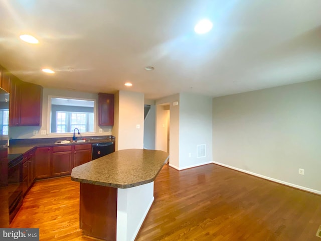 kitchen with stove, sink, hardwood / wood-style floors, and black dishwasher