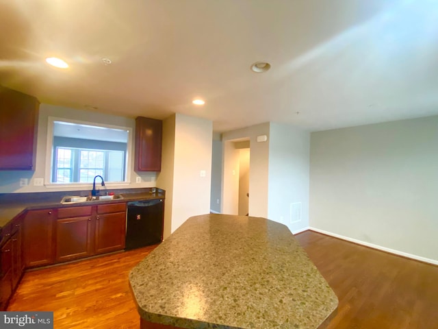 kitchen featuring light stone counters, sink, dark wood-type flooring, and black dishwasher