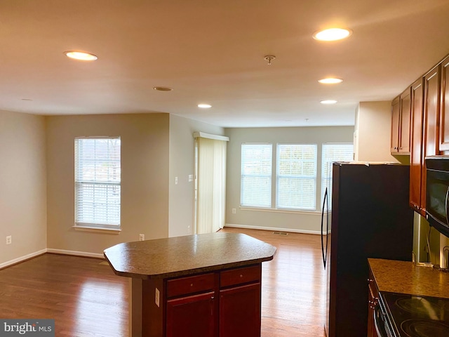 kitchen with a kitchen island, hardwood / wood-style floors, and black range with electric cooktop