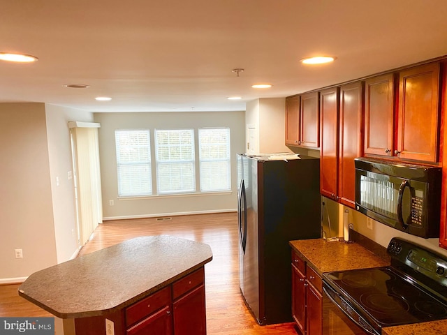 kitchen featuring light wood-type flooring, a kitchen island, and black appliances