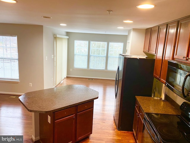 kitchen with a center island, light hardwood / wood-style flooring, and black appliances