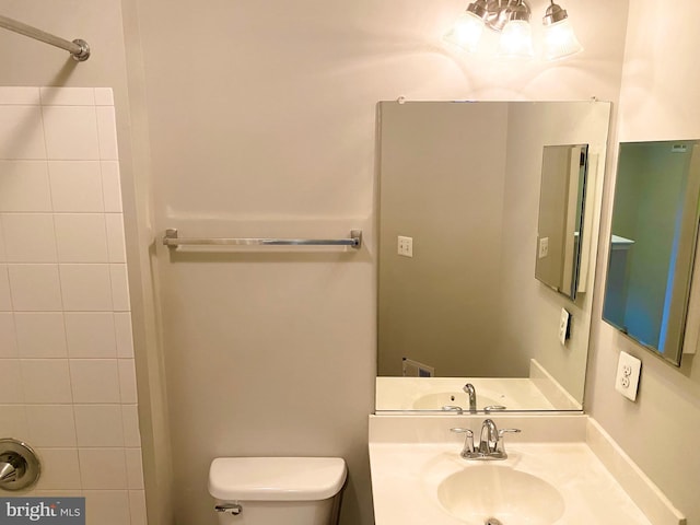 bathroom with toilet, sink, and a tile shower