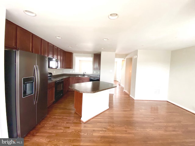 kitchen with sink, hardwood / wood-style floors, black appliances, and a center island