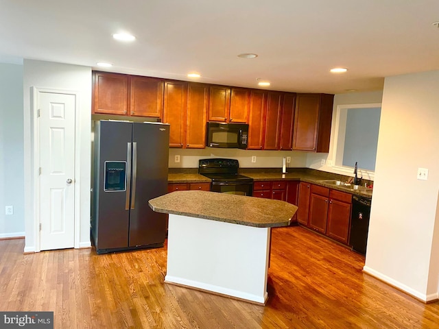 kitchen featuring a center island, sink, light hardwood / wood-style flooring, and black appliances