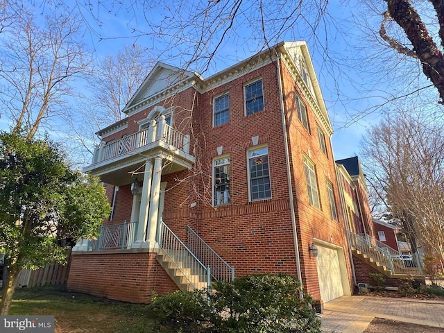 view of front of house with brick siding, stairway, concrete driveway, and a garage