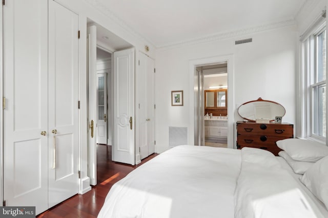 bedroom featuring ornamental molding, connected bathroom, and dark hardwood / wood-style flooring