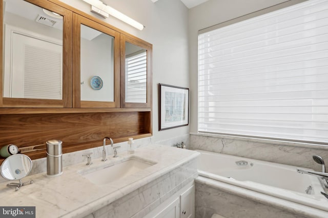 bathroom with tiled tub and vanity