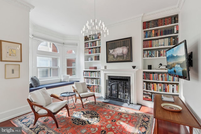 sitting room featuring crown molding, built in features, hardwood / wood-style flooring, and a chandelier