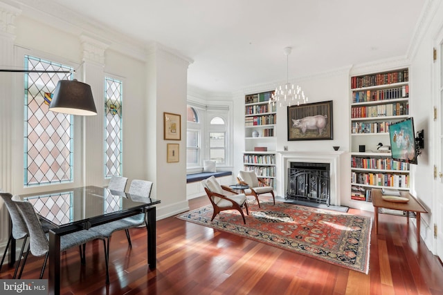 living area with built in shelves, a chandelier, ornamental molding, and dark hardwood / wood-style flooring