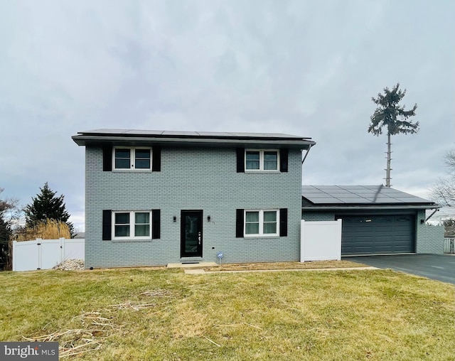 view of front of house featuring a garage, a front yard, and solar panels