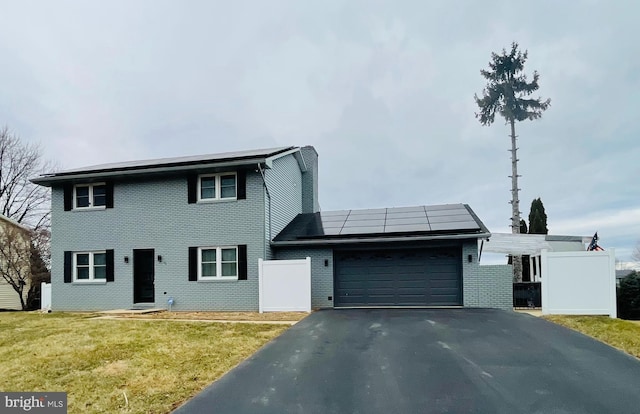 view of front of property with an attached garage, solar panels, fence, driveway, and a front lawn