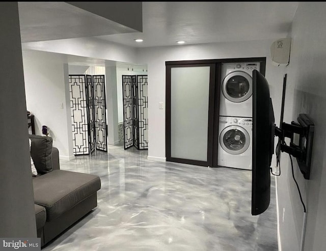 laundry area with laundry area, recessed lighting, stacked washer and clothes dryer, and baseboards