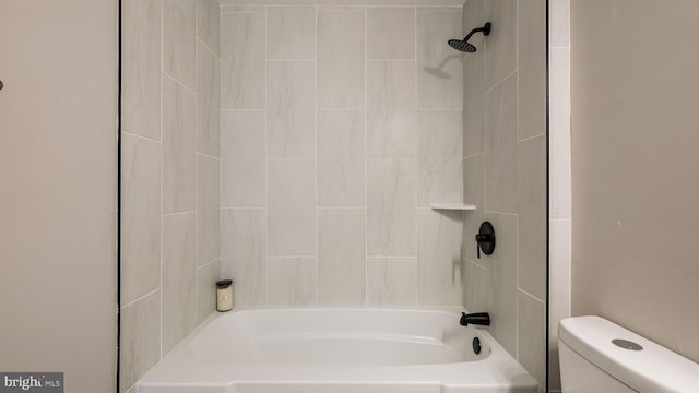 bathroom with toilet and tiled shower / bath