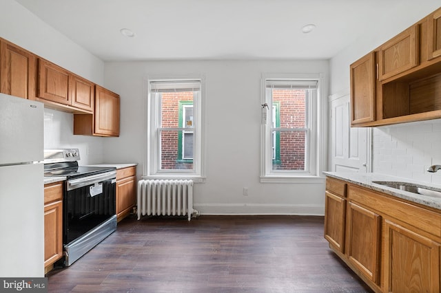 kitchen featuring white refrigerator, a healthy amount of sunlight, radiator, and stainless steel range with electric stovetop