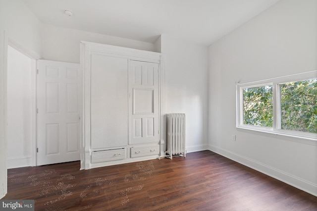 unfurnished bedroom with radiator and dark hardwood / wood-style flooring