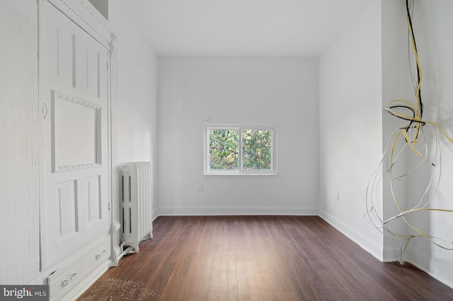 empty room featuring dark wood-type flooring and radiator heating unit