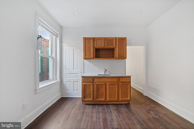 bar with dark wood-type flooring, sink, backsplash, and light stone countertops