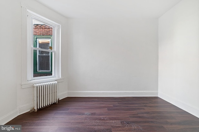 spare room featuring a wealth of natural light, dark hardwood / wood-style floors, and radiator heating unit