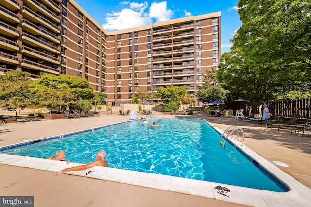 community pool with a patio area and fence