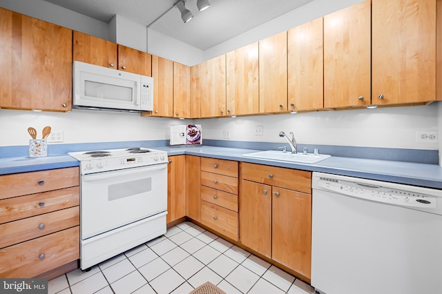 kitchen featuring brown cabinets, white appliances, light countertops, and a sink