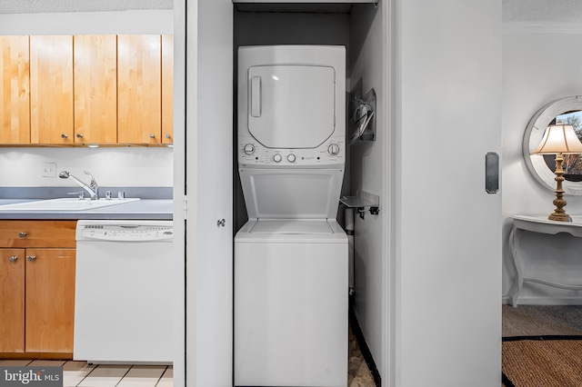 laundry area with stacked washer / drying machine, laundry area, and a sink