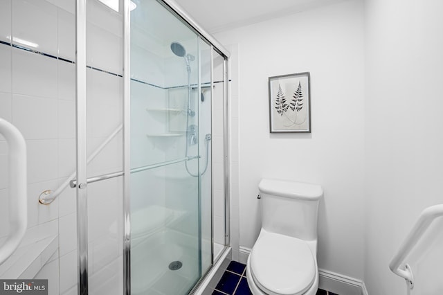 bathroom featuring toilet, a shower stall, and baseboards